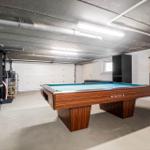 Billiard table with blue felt in a garage with seating and grill.
