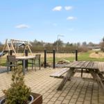 Terrasse mit Picknicktisch, Tisch und Stühlen, Spielplatz und Grünfläche im Hintergrund.