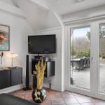 Wohnzimmer mit TV, Schwebetüren und Terrasse mit Gartenmöbeln.