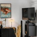 Wohnzimmer mit Fernseher, Beistelltisch und Wandbild.