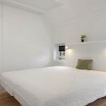 Schlafzimmer mit weißem Bett, Kleiderschrank und Fenster