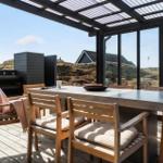 Terrasse mit Tisch und Stühlen, Blick auf Hügel und Gebäude.