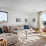 Wohnzimmer mit Sofa, Sitzgelegenheit und Blick auf Balkon.