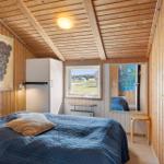 Schlafzimmer mit Holzwand, Bett, Fenster und Kühlschrank.