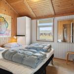 Schlafzimmer mit Holzwand, Bett, Fenster und Spiegel