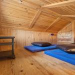 Zimmer mit Holzwand, Holzdecke und zwei blauen Matratzen mit Kissen.