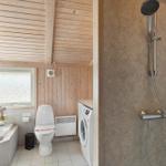 Bad mit Dusche, Toilette und Waschmaschine. Holzwände und Fenster.