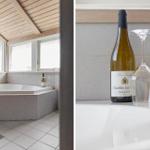 Bad mit Whirlpool und Fenstern. Weißer Tisch mit Weinflasche und Gläsern.