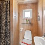 Badezimmer mit Holzwand, Toilette, Waschbecken und Duschvorhang mit Muster.