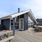 Moderne Strandhütte mit großem Holzterrasse, Sitzgelegenheiten und Blick auf das Meer.