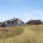 Moderne Villa mit Holzverkleidung und großen Fenstern auf grünem Grundstück.