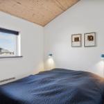 Schlafzimmer mit blauem Bett, Holzdecke und Fensterblick auf Haus