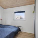Schlafzimmer mit Bett, Fenster und Holzdecke.