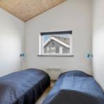 Zwei Betten mit blauen Bettdecken, Wandbild und Fenster mit Blick auf ein Haus.