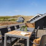 Terrasse mit Tisch und Stühlen, Blick auf Dünen und Haus.