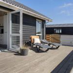 Terrasse mit Liegestühlen und Blick ins Haus. Holzdeck und Schiebetür.