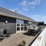 Terrasse mit Tisch und Stühlen vor einem Haus mit dunkler Fassade und Glasfenstern.