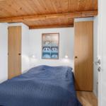 Schlafzimmer mit Bett, Holzdecke und zwei Türen.