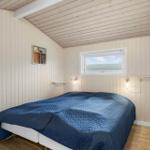 Schlafzimmer mit Bett, Fenster und Holzwandverkleidung.