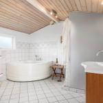 Badezimmer mit Badewanne, Waschbecken und Toilette. Holzdecke und Fliesenboden.