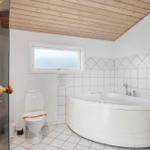 Badezimmer mit Whirlpool, Toilette und Sauna. Holzdecke und Fliesenwand.