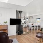 Wohn- und Essbereich mit Holzboden, TV, Kamin und Essplatz mit Tisch und Stühlen.