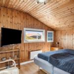 Schlafzimmer mit Holzwand, Bett, Fernseher und Fensterblick.