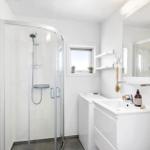 Badezimmer mit Duschkabine, Waschmaschine und Spiegelschrank.