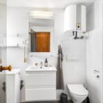 Badezimmer mit Waschbecken, Spiegel, Toilette und Dusche.