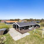 Moderne Ferienhaus mit Terrasse, Schaukel und Garten. Hintergrund: Grünfläche und andere Häuser.