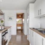 Küche mit Holz Arbeitsplatte, weißen Schränken und Edelstahlspüle.