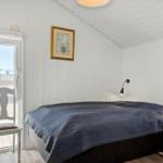 Schlafzimmer mit Bett, Wandlampen und Tür zum Balkon.