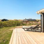 Terrasse mit Liegestühlen neben einem Haus. Im Hintergrund sind weitere Häuser und Dünen zu sehen.