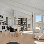 Wohnküche mit Esstisch, TV und Terrasse. Weiße Wände, Holzboden und Glasfront.
