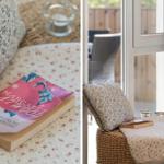 Ein Buch liegt auf einem floralen Kissen. Durch ein Fenster ist ein Balkon mit Stuhl sichtbar.