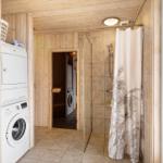 Dusche mit Duschvorhang, Waschmaschine und Trockner in Holzvertäfelung
