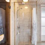 Dusche mit Glaswand, Duschbrause und gefliesten Wänden. Fenster mit Milchglas.