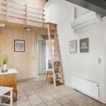 Hallenraum mit Holzwand, Treppe zur oberen Etage und Wandbildern.