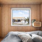 Schlafzimmer mit Holzwand, Bett und Fensterblick auf Baustelle.