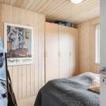 Schlafzimmer mit Holzwand, Bett, Kleiderschrank und Wandbild.