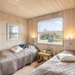 Zwei Betten in einem Zimmer mit Holzwänden und Fensterblick auf Grünflächen.