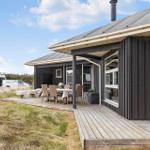 Moderne Holzhütte mit Terrasse und Gartenmöbeln. Hintergrund: Baustelle und Himmel.