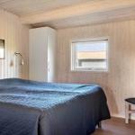 Schlafzimmer mit Bett, Stuhl und Fenster. Wände aus Holz, Bilder an der Wand.