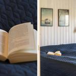 Ein Buch liegt auf einem Bett mit dunkelblauer Decke. An der Wand hängen zwei Bilder.