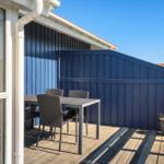 Terrasse mit Tisch und Stühlen, blauer Holzaufbau und Pflanze