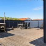 Terrasse mit Holzboden, Sitzgruppe, Liegestühlen und Whirlpool. Umzäunt mit dunkelblauem Holzzaun.