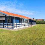 Ein Haus mit blauem Holzschindelgehäuse und rotem Dach. Vorne befindet sich eine Terrasse mit weiß-blauer Brüstung.