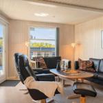 Wohnzimmer mit schwarzen Ledersofas, Holztisch und Blick auf Balkon.