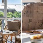 Sitzgelegenheit mit Tisch und Pflanze vor großem Fenster. Bücher auf Polsterbank mit floraler Tapete.