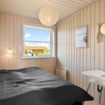 Schlafzimmer mit Bett, Fenster und Hochstuhl. Holzwände und Decke.